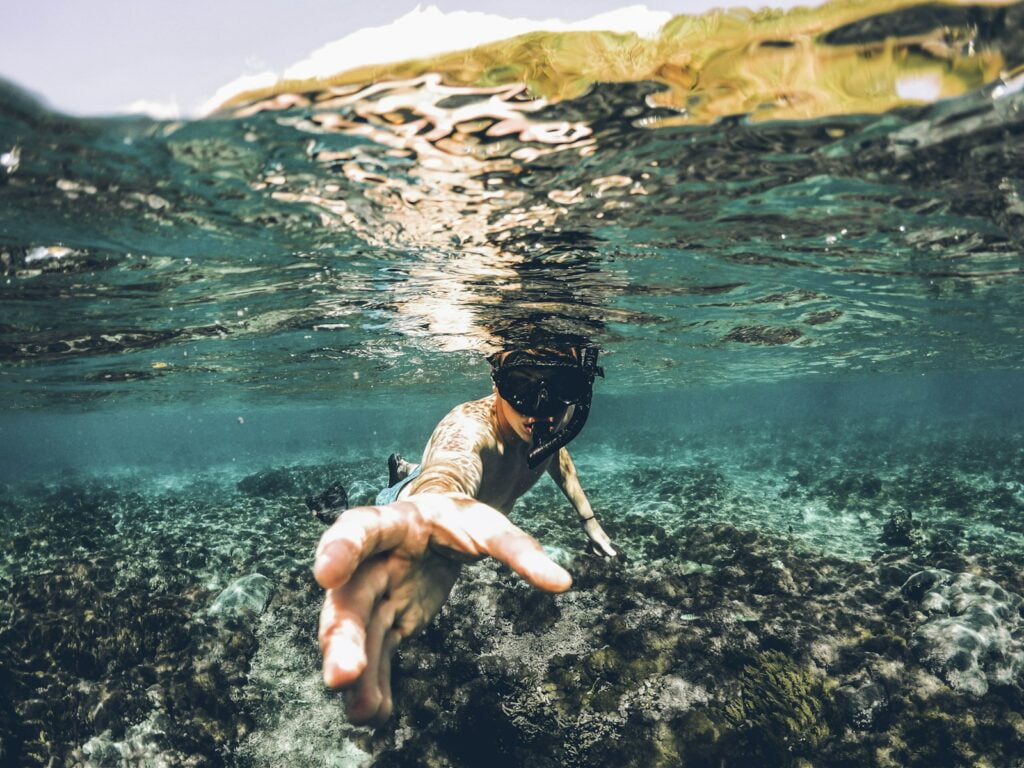 Blog 3 actividades al aire libre en los cristianos - underwater photography of man wearing snorkel lending his hand